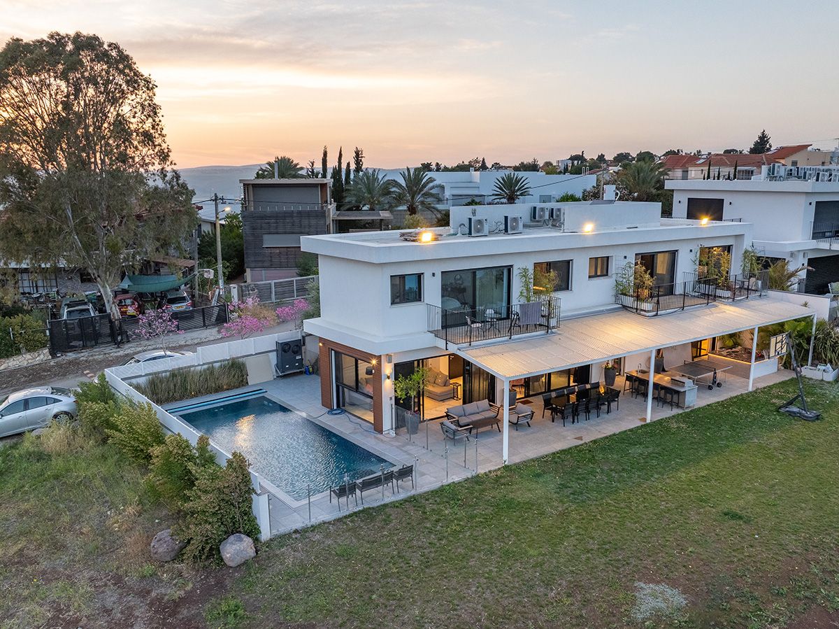 La villa illuminée au coucher du soleil, avec sa piscine, son jardin et sa terrasse couverte